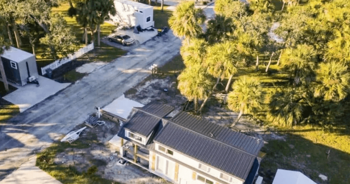 Colorful patchwork tiny home with red, yellow, and brown siding on a grassy lot at Peacewind near Cocoa, Florida.